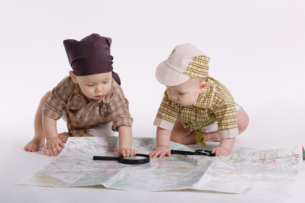 Two children playing with magnifying glasses on a map